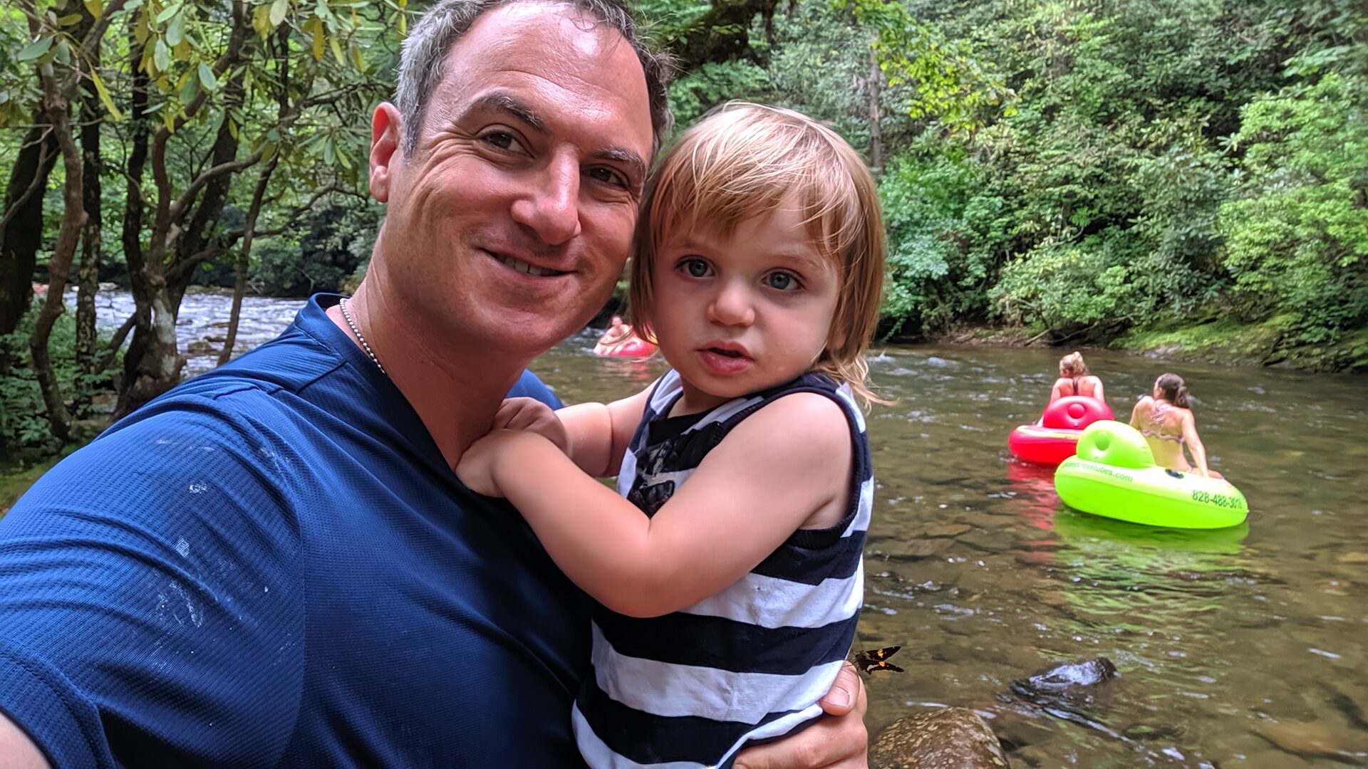 Family selfie by Deep Creek with tubers floating in the background near Bryson City NC