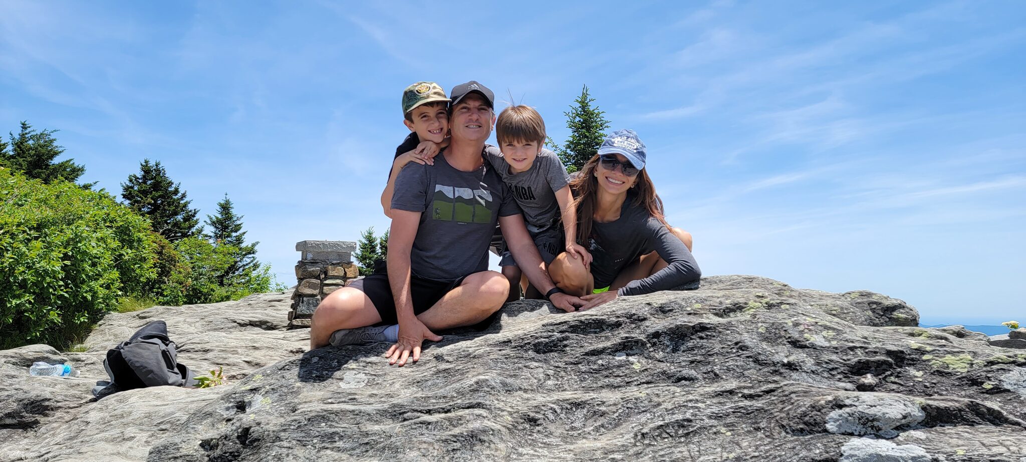 Family sitting on summit rocks at Devil's Courthouse enjoying the panoramic Blue Ridge Mountain views