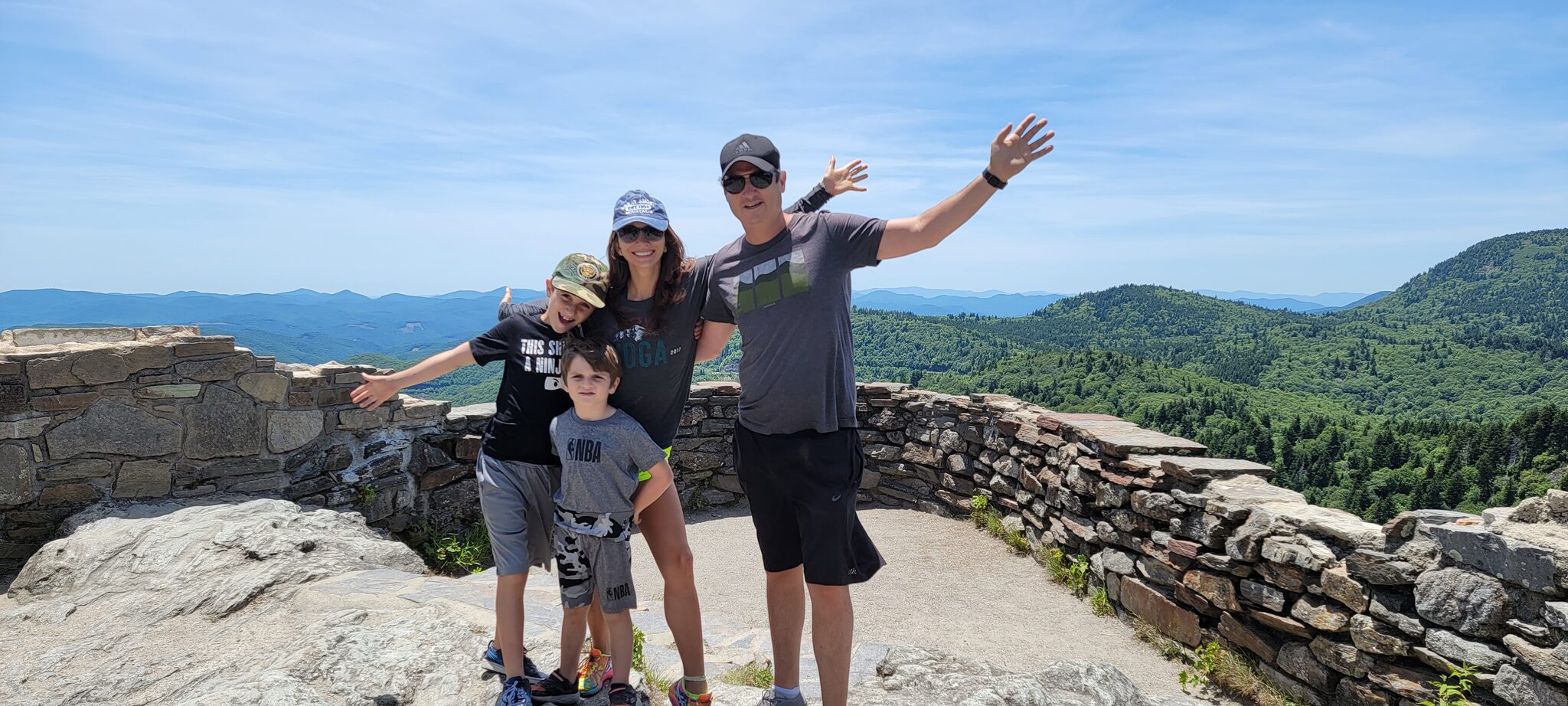 Family at the Devil's Courthouse summit overlook with stone wall and mountain views stretching to the horizon
