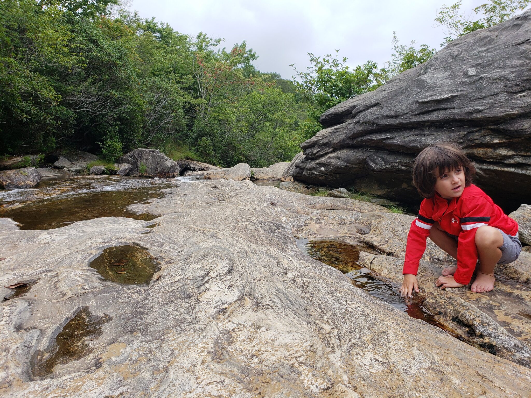 Child exploring rock formations along the creek at Graveyard Fields