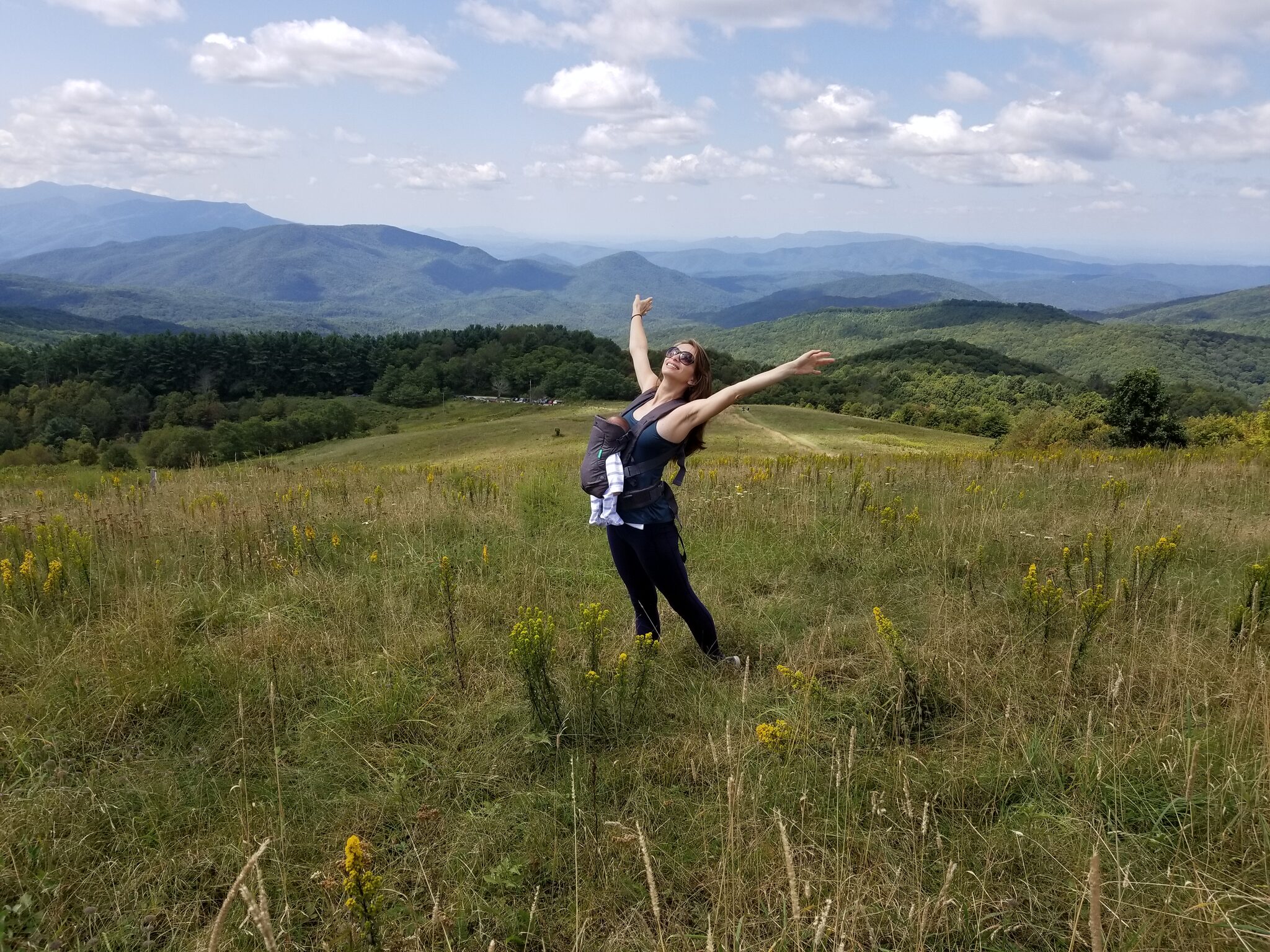 Joyful hiker on the open grassy summit of Max Patch with 360-degree mountain views
