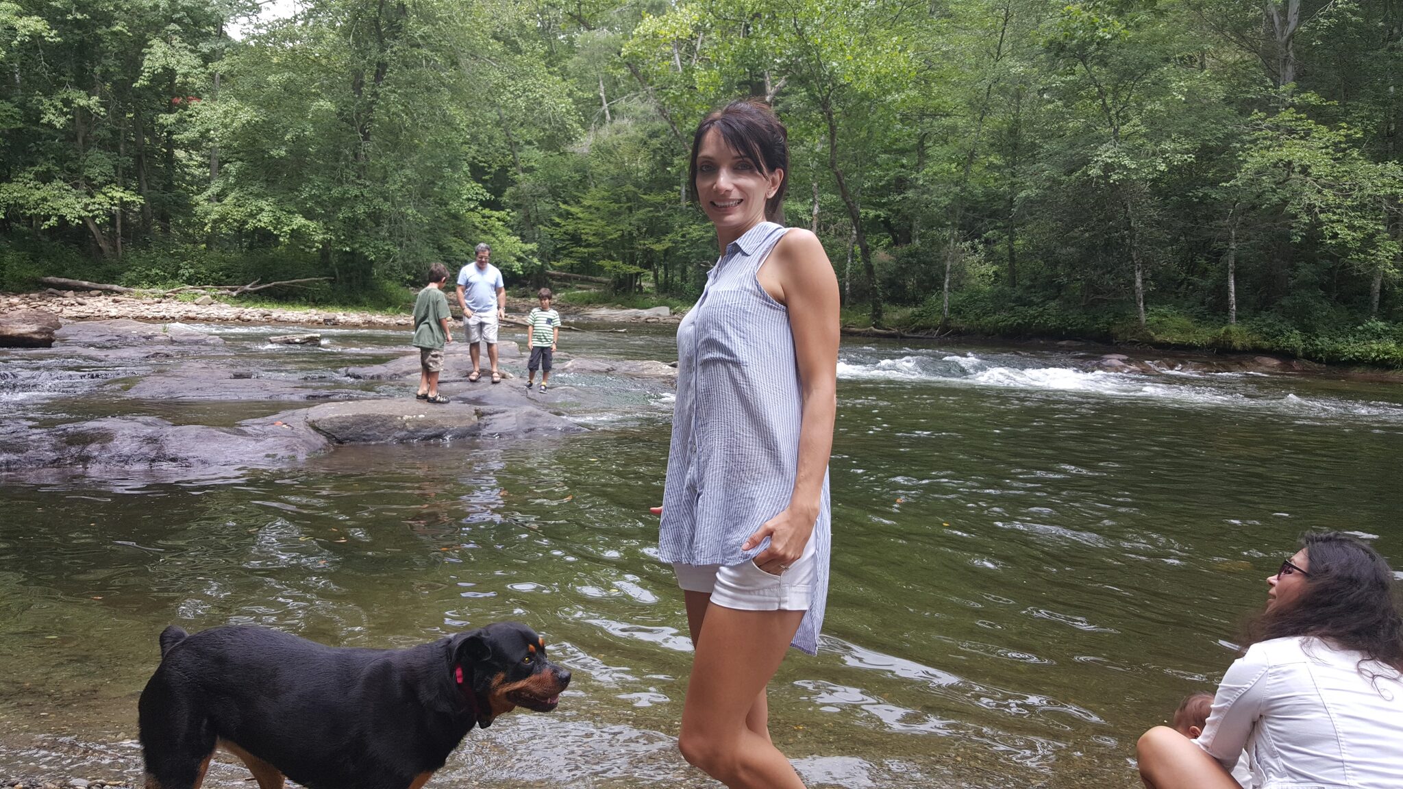 Family enjoying the Oconaluftee River with dog on a summer day in the Smokies